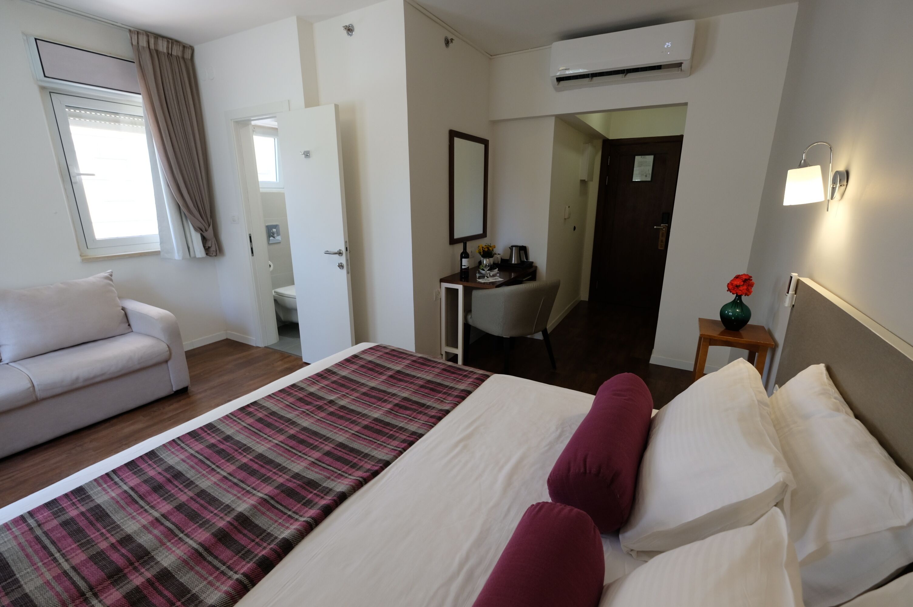 A hotel room with a bed, a sofa, a desk, and a chair.