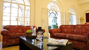 Una habitación con dos sofás rojos con estampado floral, una mesa de centro de vidrio y amplias ventanas de arco.