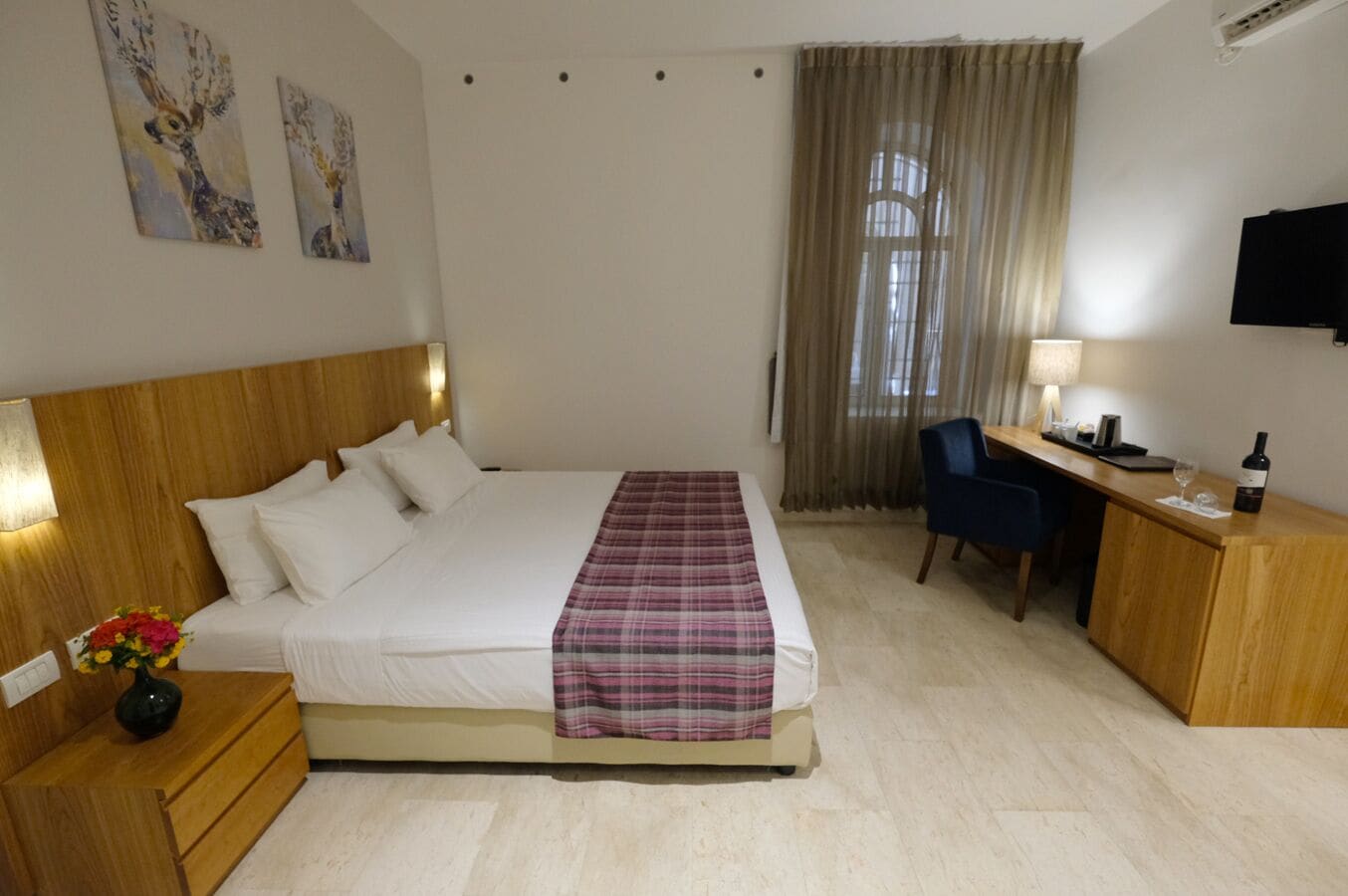 Habitación de hotel con cama, escritorio, silla, televisión y una obra de arte en la pared.