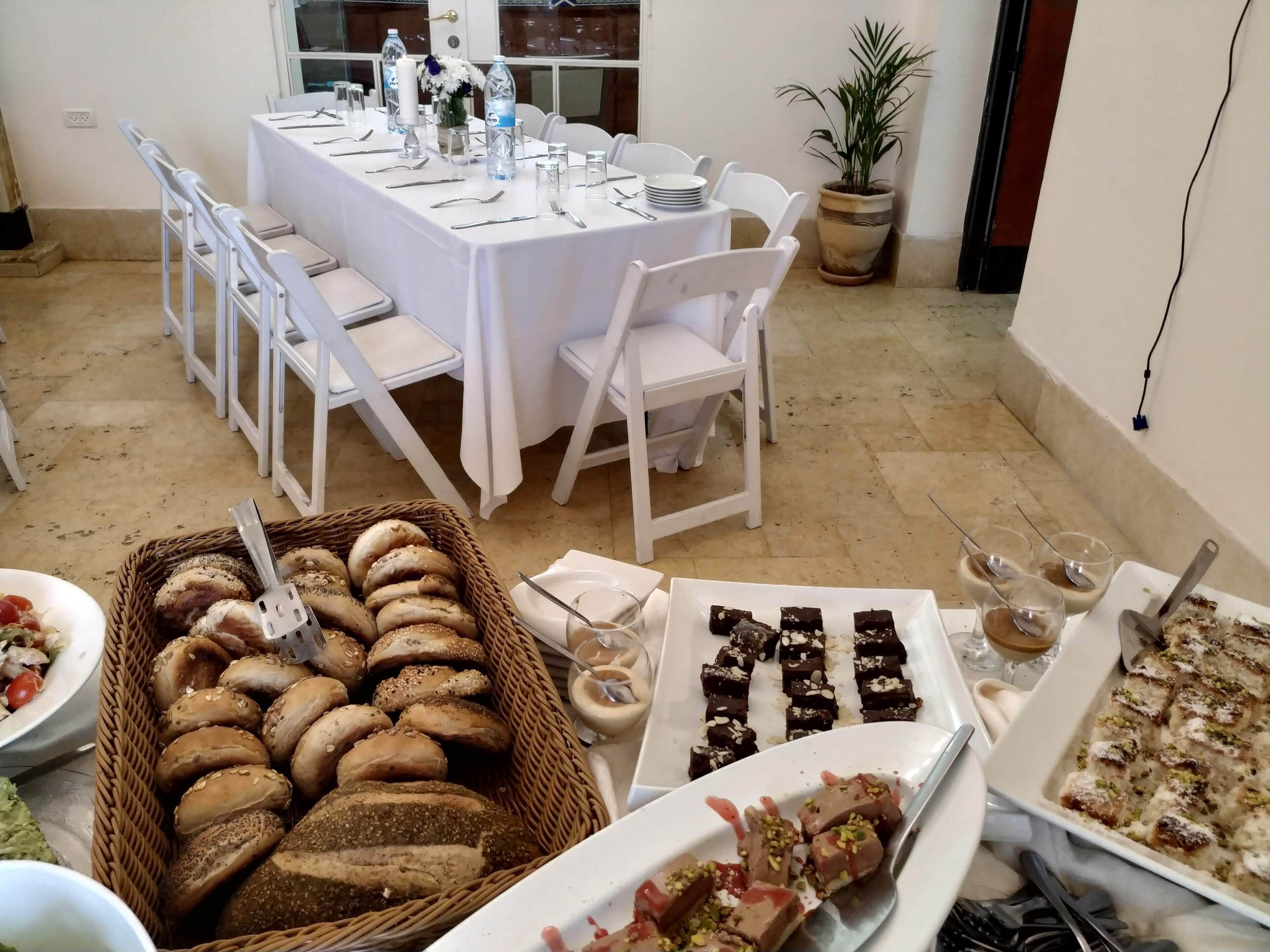 A dining area with a long table set for a meal, surrounded by white chairs.