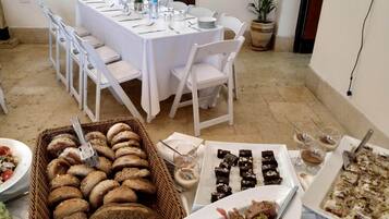 A dining area with a long table set for a meal, surrounded by white chairs.