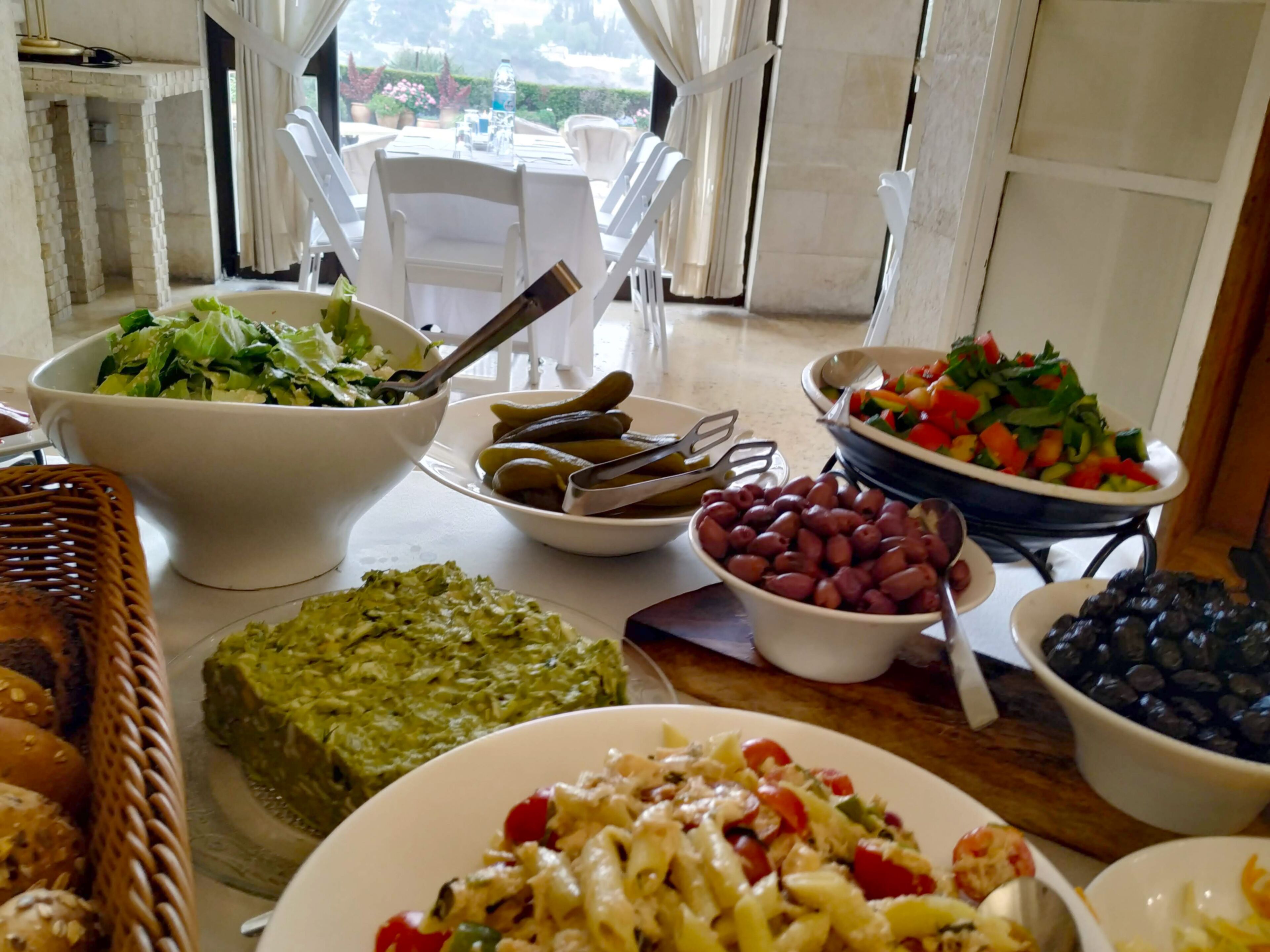 Una mesa de comedor con diferentes alimentos, como ensaladas, aceitunas y pan.