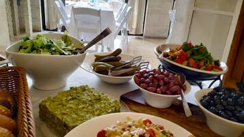 Una mesa de comedor con diferentes alimentos, como ensaladas, aceitunas y pan.