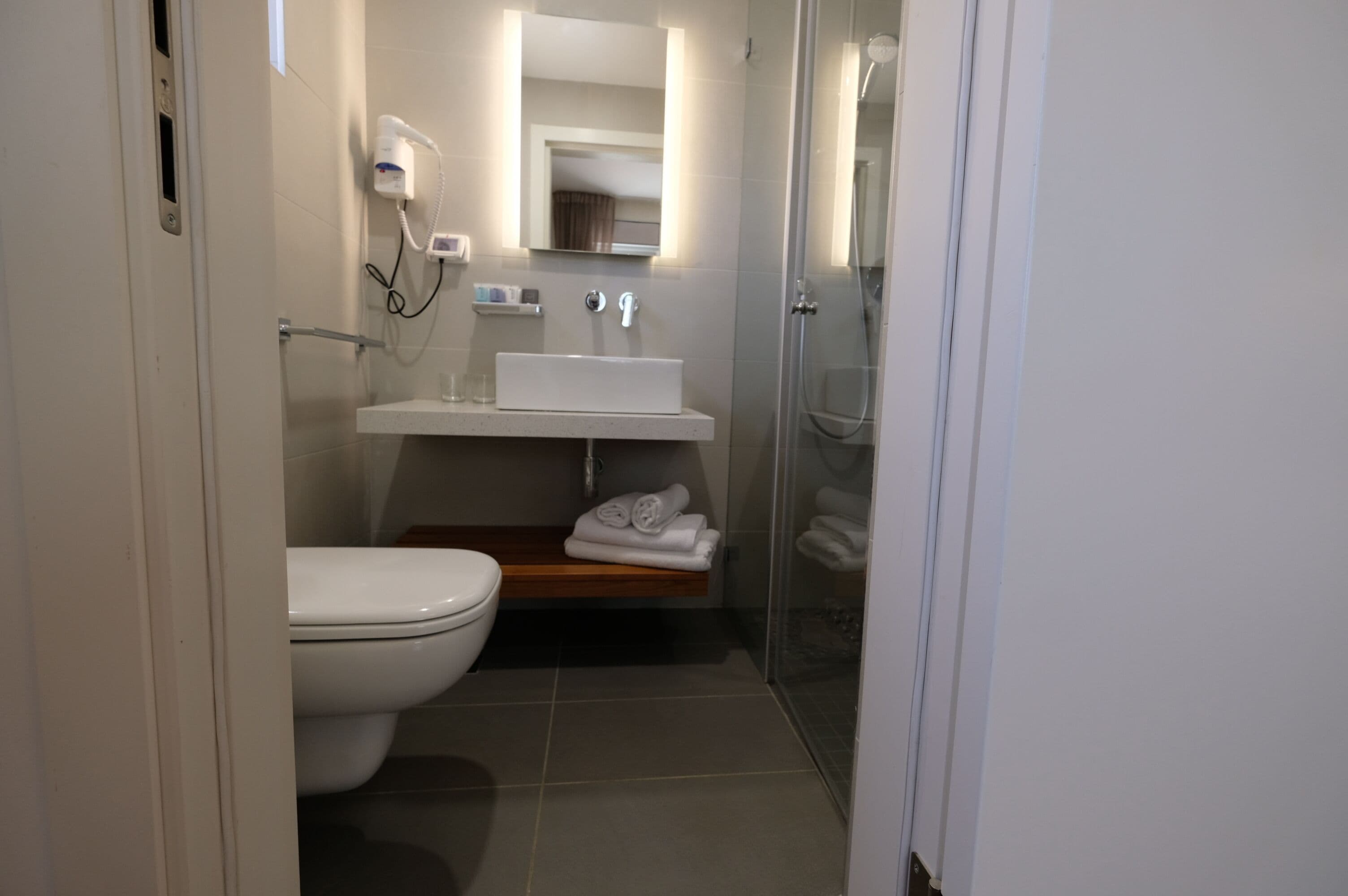 Un baño pequeño con inodoro, lavabo, espejo y ducha.