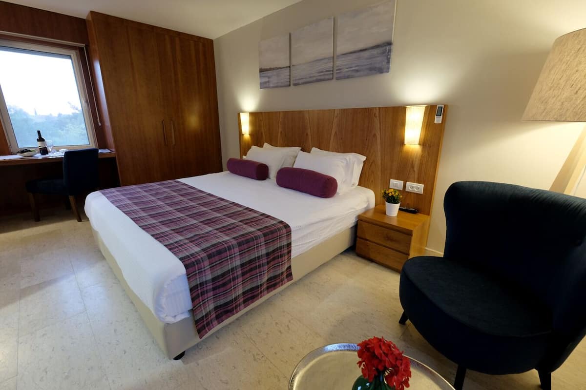 A modern hotel room with a large bed, a desk, and a chair.