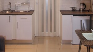 A modern kitchen with white cabinets, a microwave, a sink, and a chandelier. - Hesperus Street (Alberton)
