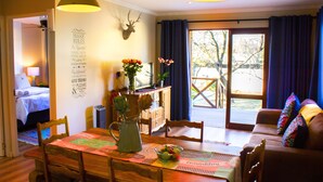 A dining area with a wooden table, chairs, a vase with flowers, and a wall with a deer head and text. - Hesperus Street (Alberton)