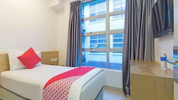 Habitación de hotel con cama, escritorio, ventana con cortinas y televisor.