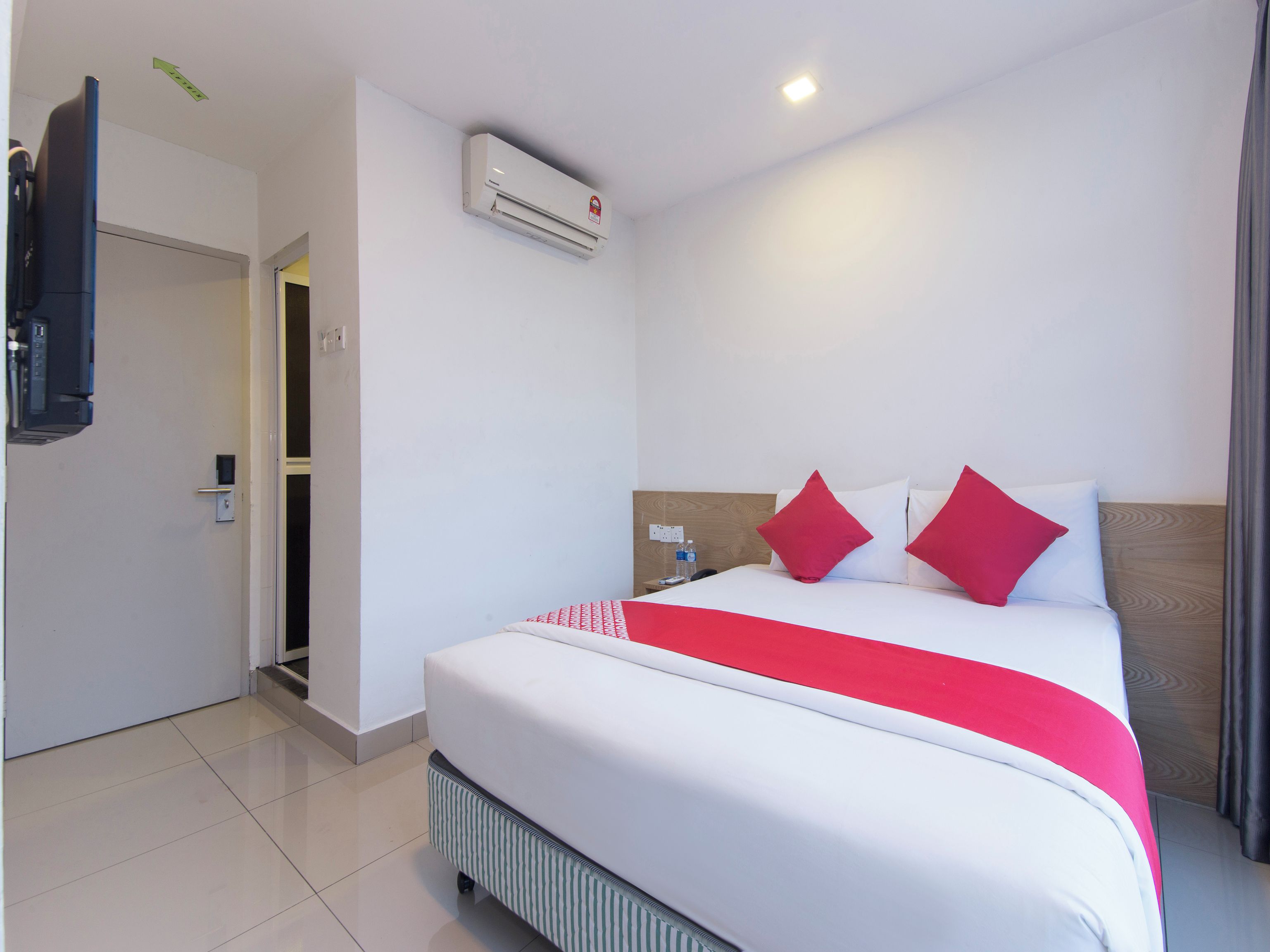 Quarto de hotel com cama, televisão, ar condicionado e porta.