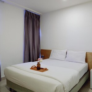 A hotel room with a bed, a wooden headboard, a nightstand, and a tray with a vase of flowers. - Iris Hotel (Kajang)
