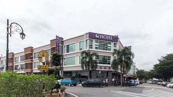 Un hotel con un cartello ben visibile, diversi piani e un'area di parcheggio.