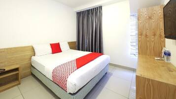 Habitación de hotel con cama, cabecera de madera, mesita de noche, espejo y ventana con cortinas.