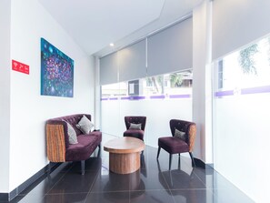 A modern lobby with a purple sofa, two armchairs, and a wooden coffee table. - Iris Hotel (Kajang)