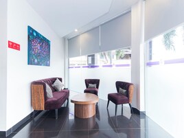 A modern lobby with a purple sofa, two armchairs, and a wooden coffee table.