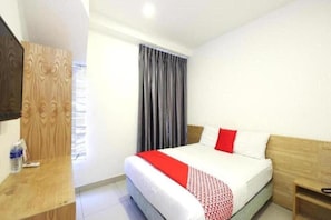 A hotel room with a bed, a wooden wardrobe, a desk, and a window with curtains. - Iris Hotel (Kajang)