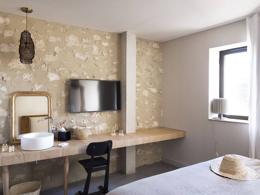 A modern bathroom with a large mirror, a sink, a television, and a window with curtains.