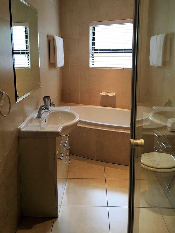 Un baño con lavamanos, espejo y bañera.