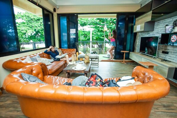 A modern living room with leather sofas, a coffee table, and a TV. - Doolay Beachfront Hostel (Karon)