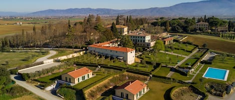 An aerial view of a large estate with multiple buildings, manicured gardens, and a swimming pool.