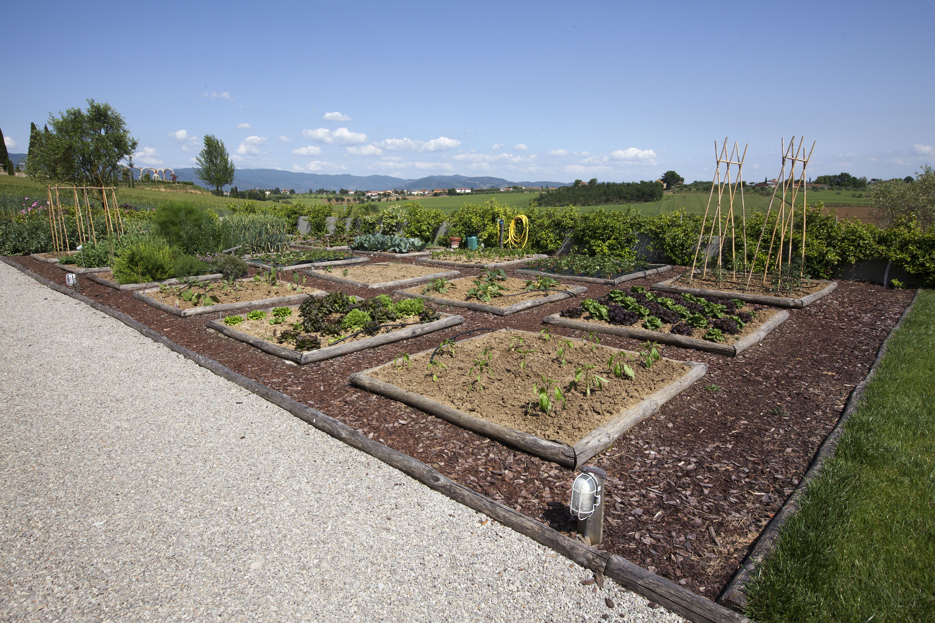 Un jardín con bancales elevados y un camino de grava.