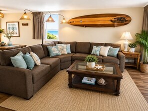 Una sala de estar con un sofá modular, una mesa de centro y una tabla de surf decorativa en la pared.