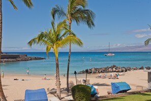 A beach with palm trees, a rocky breakwater, and a boat in the water. - Golf S G2 At Mauna Lani Resort 3 Bedroom Townhouse by RedAwning (Kamuela)