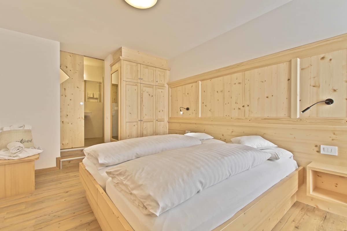 Un dormitorio de madera con cama, mesita de noche y armario.