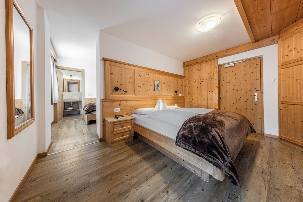 Un dormitorio con cama de madera, una mesita de noche, un aparador y un espejo.