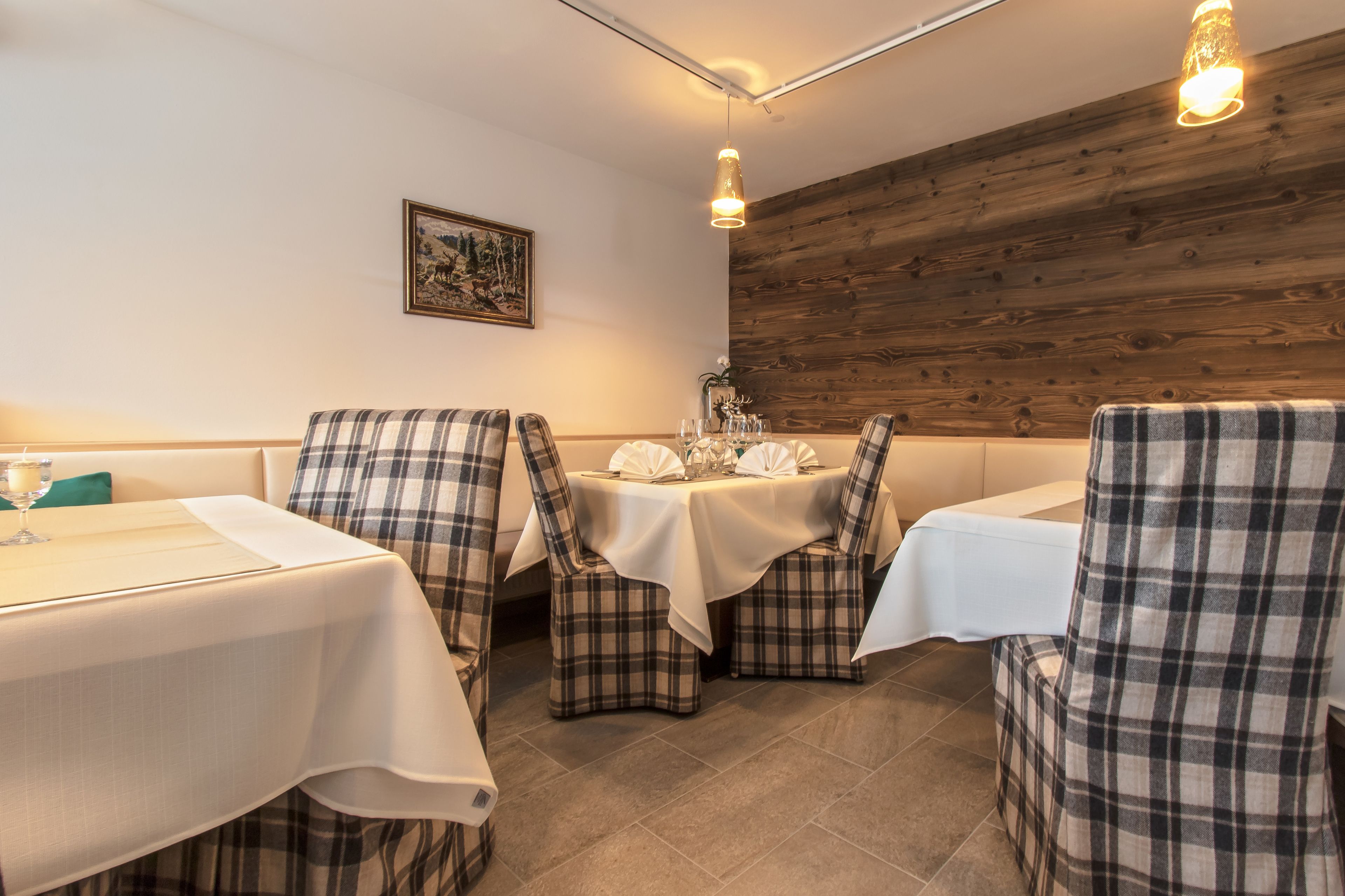 Un comedor con sillas y mesas a cuadros, paneles de madera en la pared y un cuadro enmarcado.