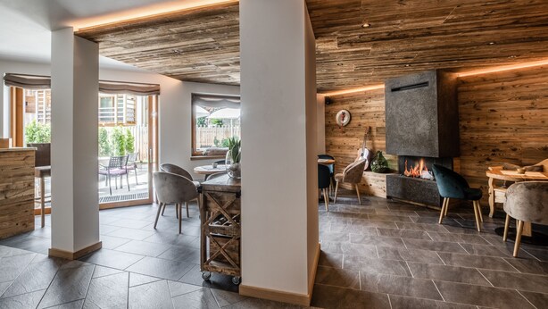 Um interior moderno com lareira, detalhes em madeira e uma área de refeições com cadeiras e mesa.