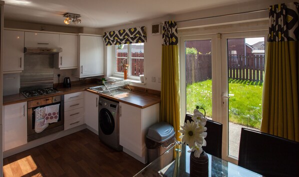 A compact kitchen with a built-in oven, a washing machine, and a gas stove. - Glasgow Hampden House (Glasgow)