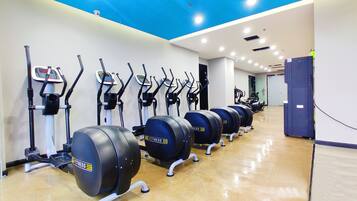 A row of fitness equipment in a gym with a polished floor and a blue ceiling.