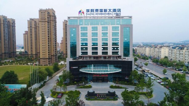Un hôtel moderne, avec une façade en verre, entouré d’immeubles résidentiels de grande hauteur.