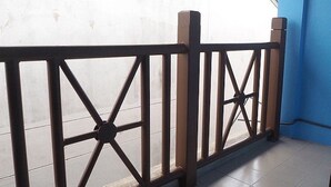 A metal fence with a crisscross pattern, a tiled floor, and a blue wall. - The Trust Guesthouse (Pak Kret)