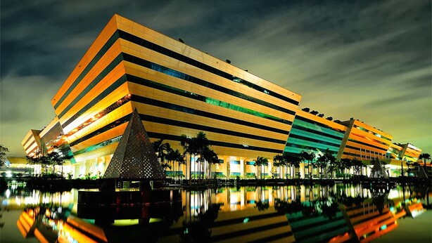 A modern building with a unique angular design, featuring multiple levels and a reflective facade. - The Trust Guesthouse (Pak Kret)