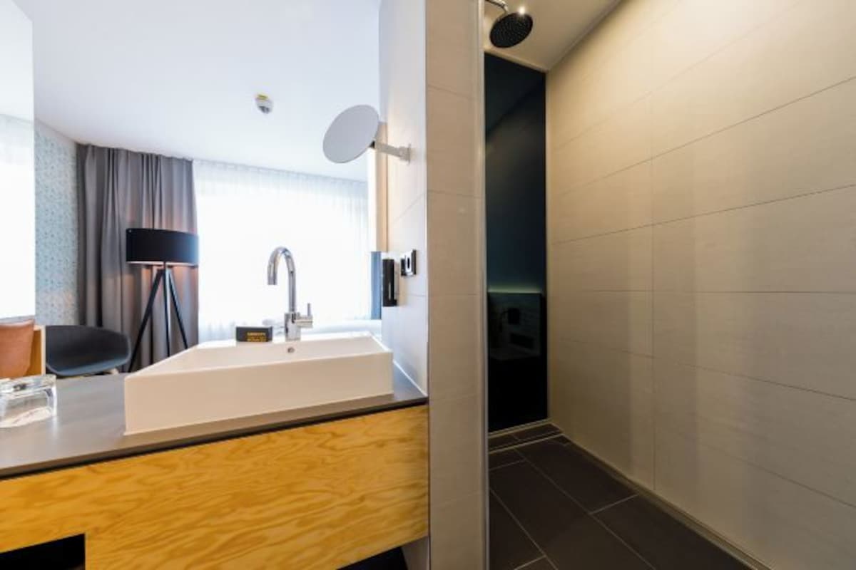 A modern bathroom with a large sink, a mirror, and a dark floor.