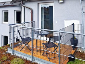 A balcony with a table and chairs, a railing, and a potted plant. - mk | hotel münchen city (Munich)