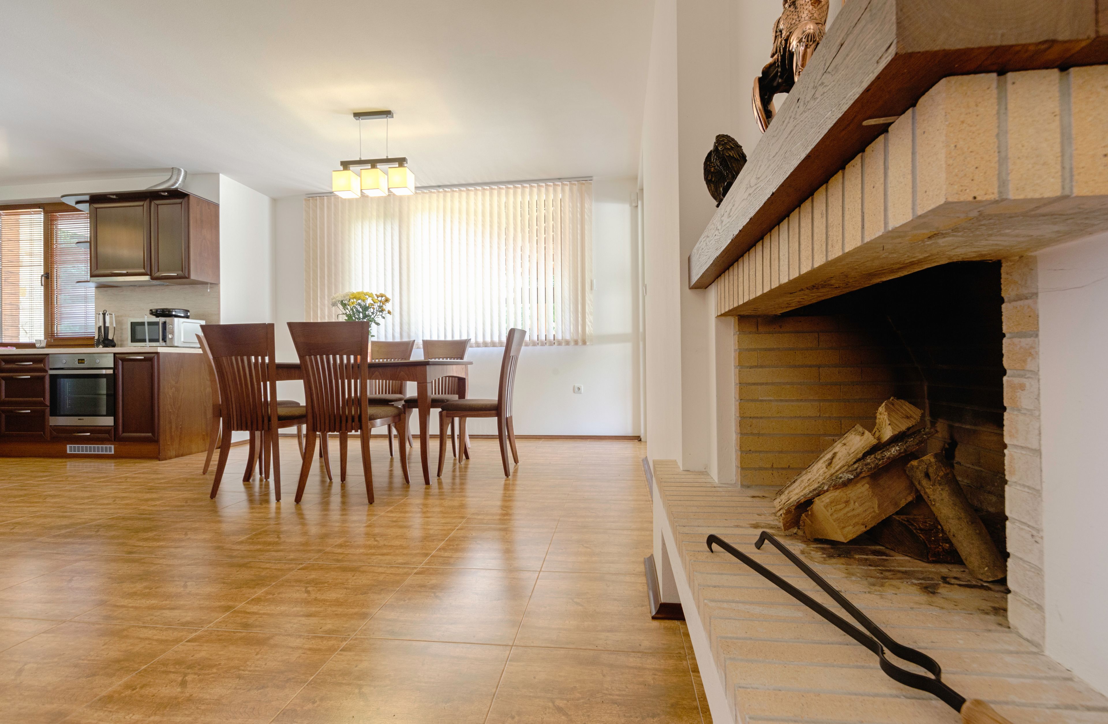 A modern kitchen with a dining area, wooden chairs, a built-in microwave, and a fireplace with logs.