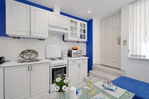 A modern kitchen with white cabinets, a stove, a microwave, and a sink. There is a vase with flowers on the counter.