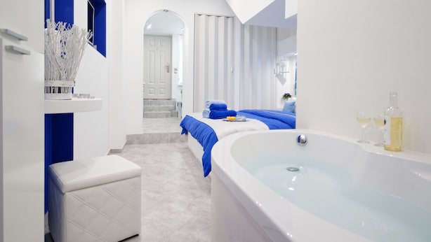 Ein modernes Badezimmer mit einer großen Badewanne, einem weißen Waschbecken und blauen Handtüchern.