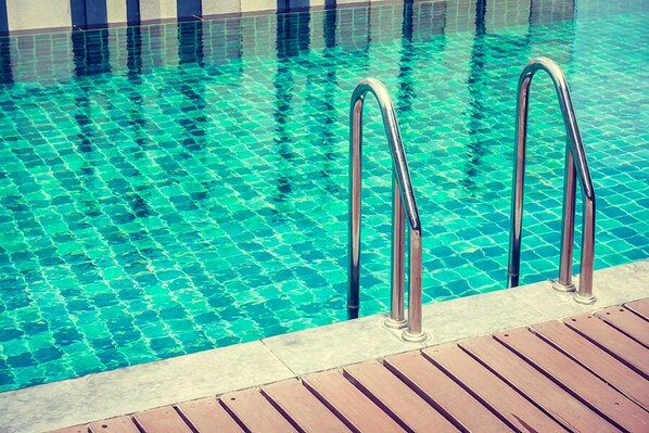 Una piscina con agua azul cristalina y escaleras metálicas.