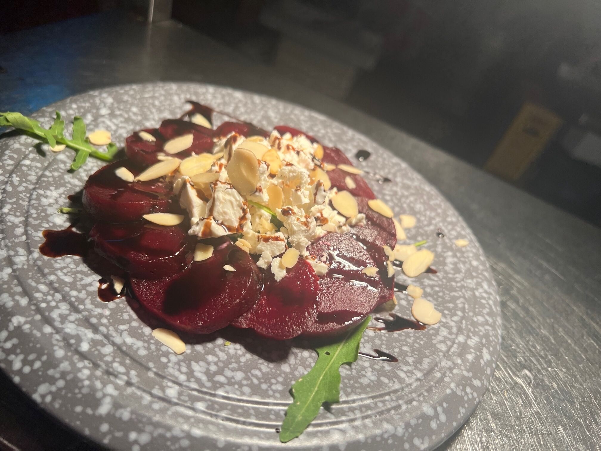 A plate of food with sliced beets, almonds, and a green garnish.