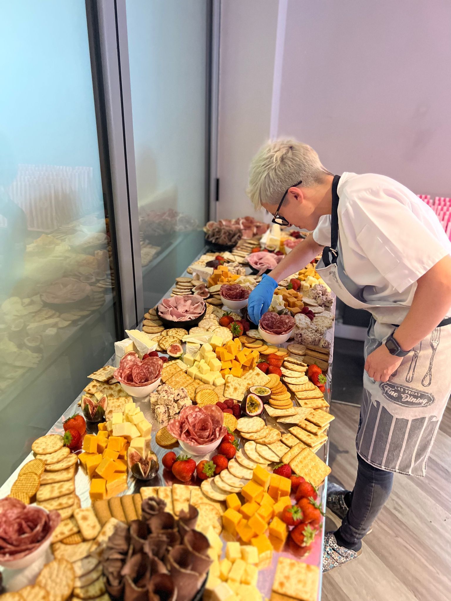 A buffet table with various cheeses, meats, and crackers.