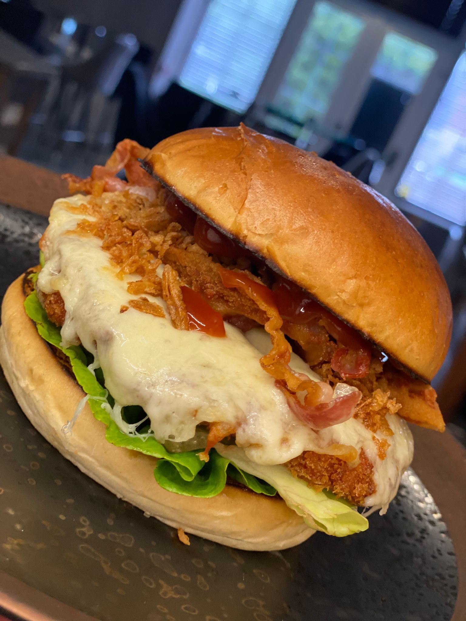 Un sándwich con lechuga, tomate y una hamburguesa de pollo frito, servido en un pan.