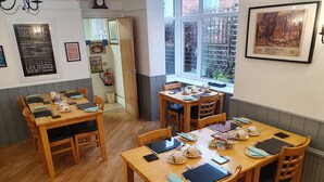 A dining area with wooden tables and chairs, equipped with tea sets and electronic devices. - The Braemar Southport (Southport)