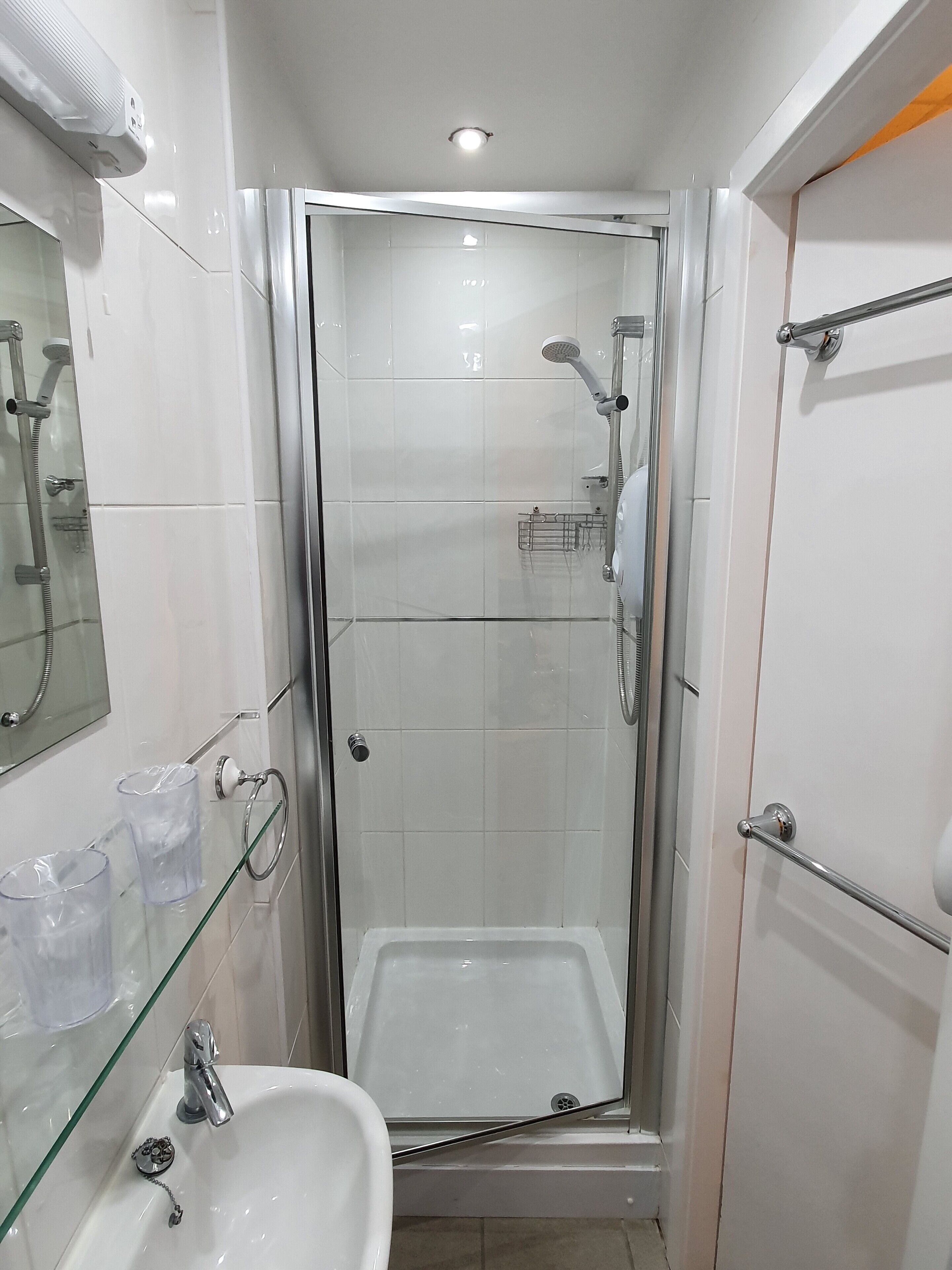 Un bagno piccolo e moderno con cabina doccia in vetro, lavandino e water.