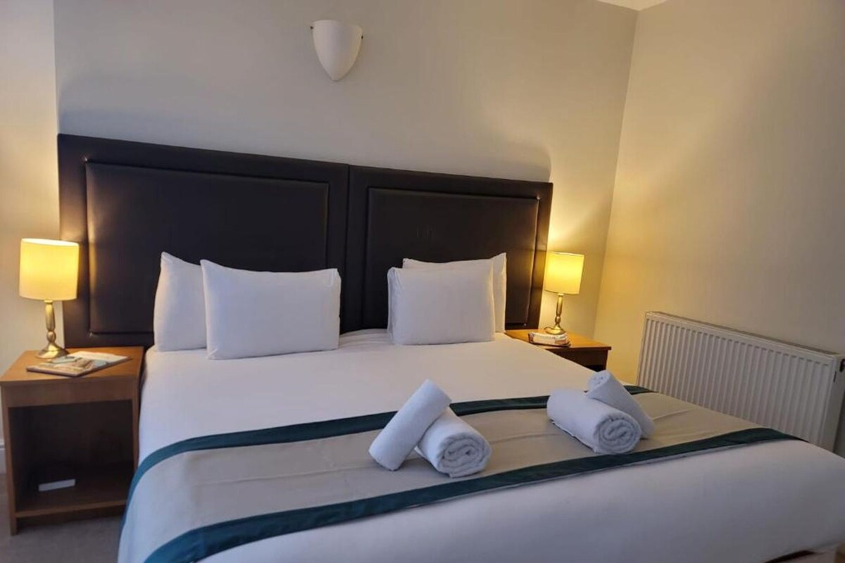 Une chambre d’hôtel avec un grand lit, deux lampes de chevet et un radiateur.