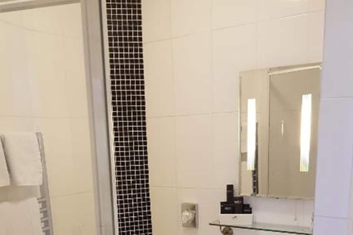 A bathroom with a glass shower enclosure, a toilet, a sink, and a mirror.