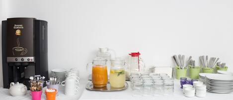 A coffee station with a Douwe Egberts coffee machine, various drink dispensers, and a tea set.