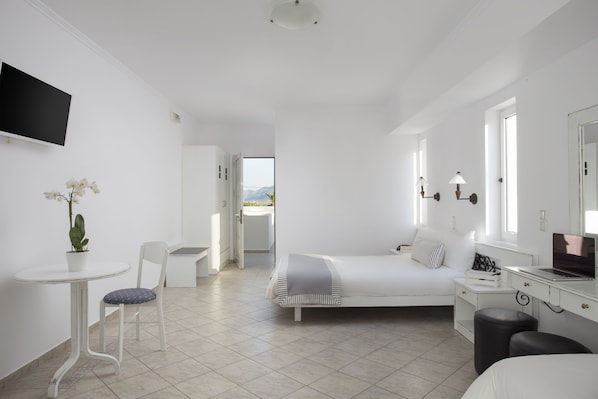 A modern, minimalist bedroom with a bed, desk, chair, and a TV mounted on the wall.